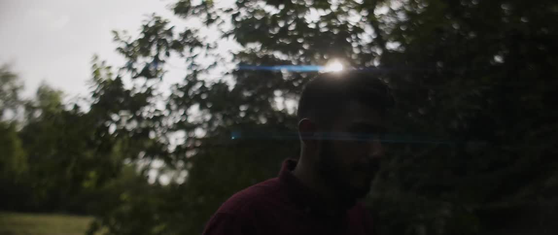 A man walks past a tree looking back