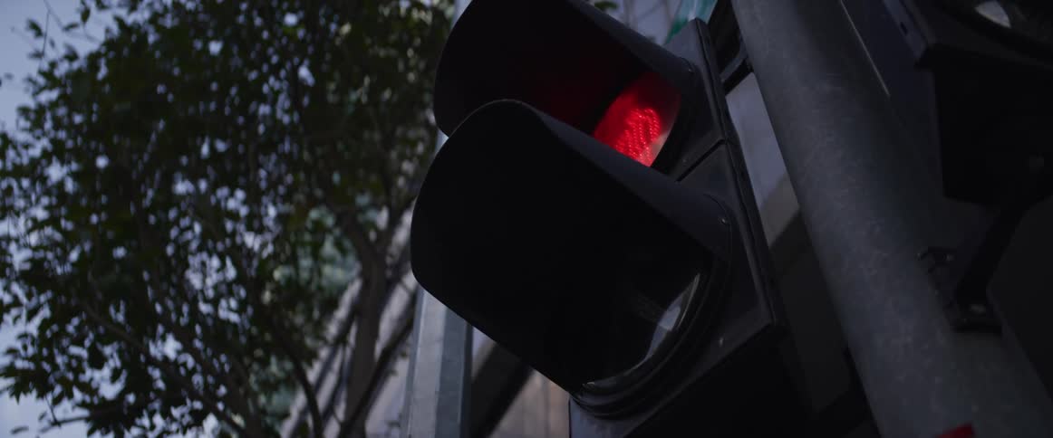 A pedestrian crosswalk traffic signal changes from a red stop hand symbol to a green walk symbol