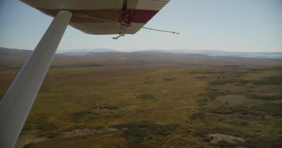 An aerial point-of-view from a small plane shows the vast, remote tundra below on a clear day