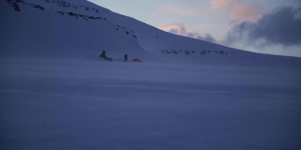 Arctic explorers endure a fierce ground blizzard as they set up camp next to a snowmobile in a vast, frozen landscape at dusk