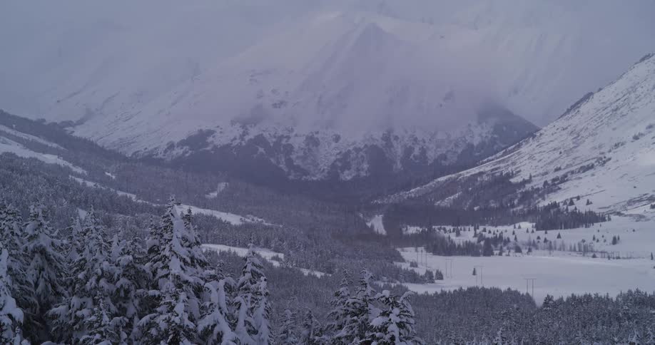 A breathtaking panoramic view of a snow-covered valley nestled between towering mountains in winter