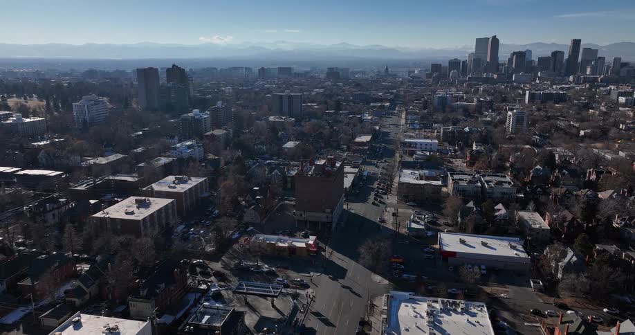 Aerial view of the Denver, Colorado cityscape slowly pushing towards the downtown skyline with the Rocky Mountains on the horizon
