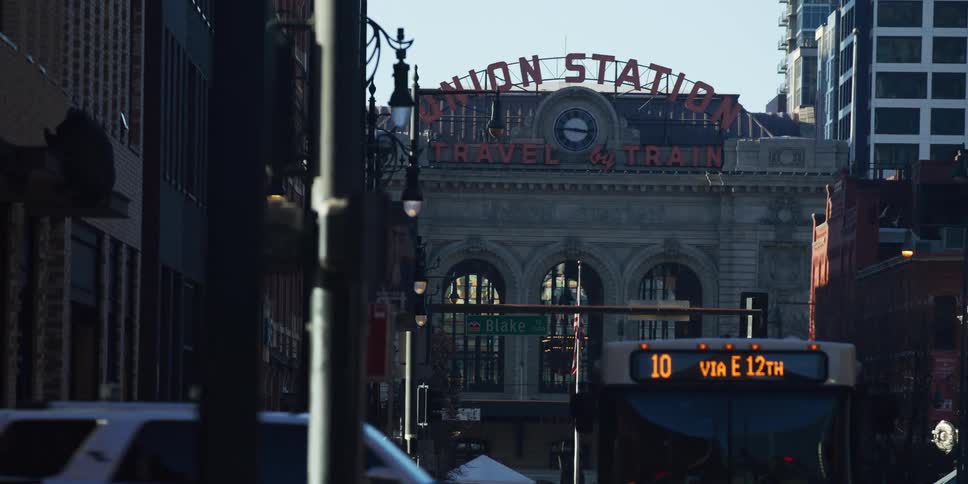 Static long shot of Denver's historic Union Station with a city bus displaying a 'Masks Required' sign during the COVID-19 pandemic