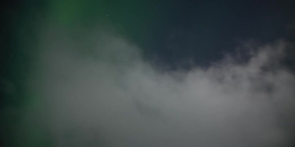 The Northern Lights shimmer in a star-filled sky before being hidden by a blanket of passing clouds in this timelapse