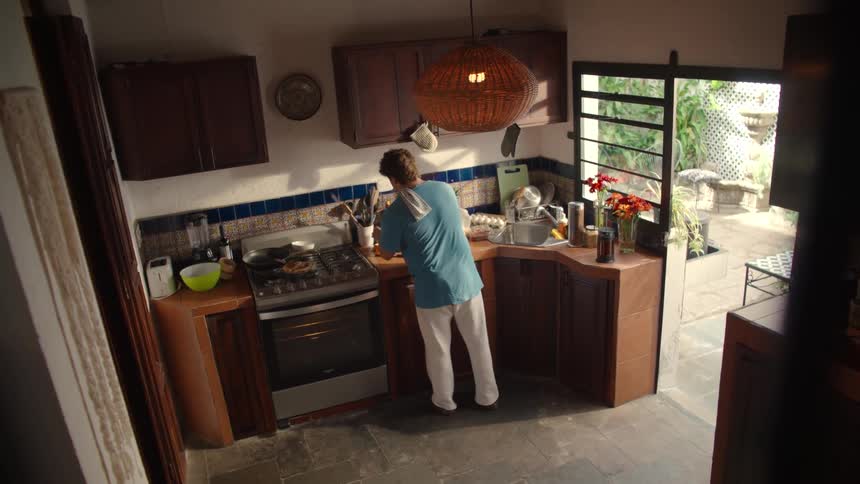 High angle view of a man making breakfast in his cozy, sunlit rustic kitchen before carrying the plate away