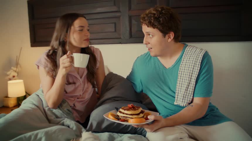 A caring husband surprises his sleeping wife by bringing her a romantic breakfast of pancakes and coffee in bed