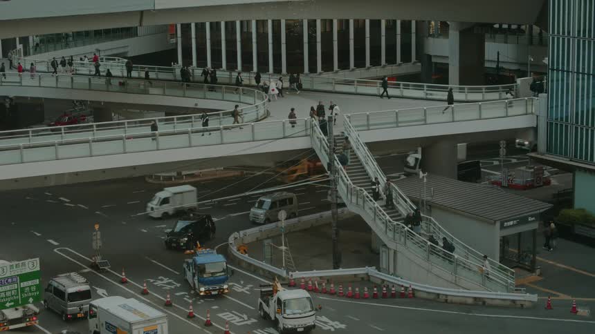 High angle view of a bustling city intersection with pedestrians walking on overpasses and cars driving on the streets below
