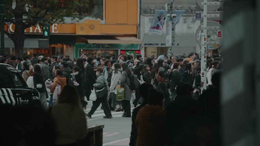 A crowd of people crosses a busy street at the Shibuya Scramble Crossing in Tokyo, Japan in slow motion