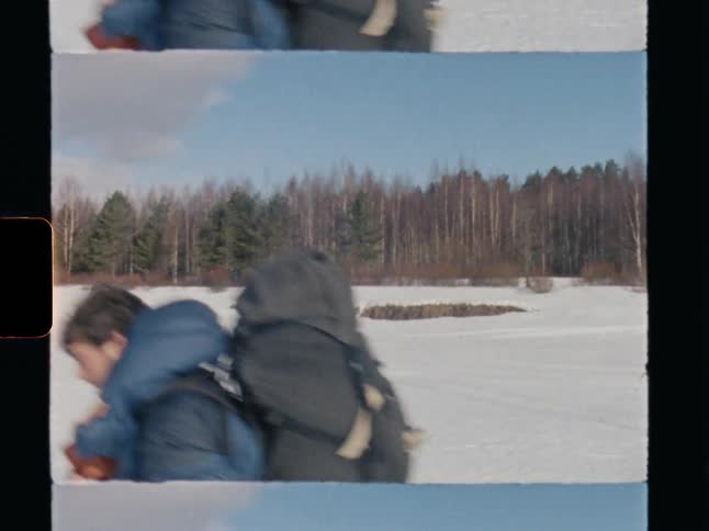 A hiker with a large backpack treks across a vast snowy landscape in this vintage 8mm film clip