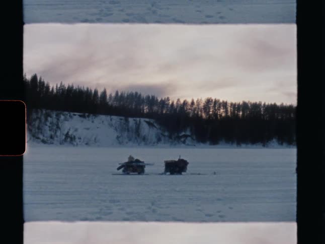 Vintage film captures two expedition sleds resting on a vast frozen river in a remote winter wilderness