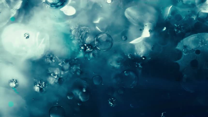 A mesmerizing macro view of ethereal blue bubbles and crystalline structures slowly drifting in liquid