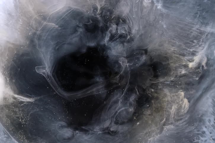 Ethereal white and gold paint creates a smoky vortex in dark water, forming an abstract and cosmic background