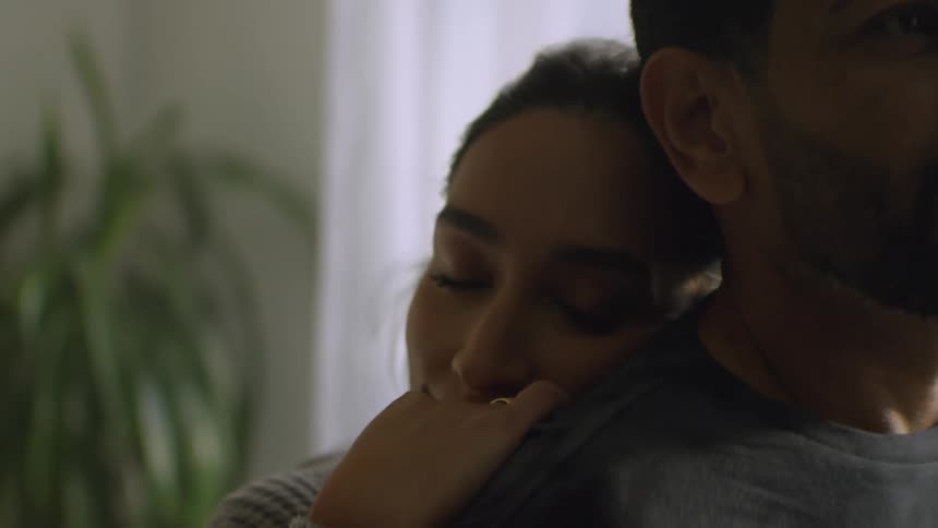 An intimate close-up of a loving woman tenderly embracing her partner from behind at home