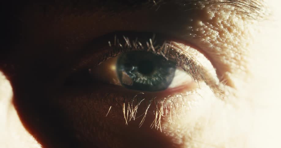 A dramatic macro shot of a blue human eye slowly closing shut