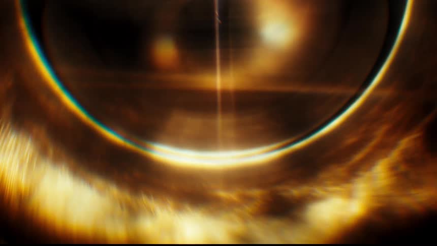 A glowing golden orb with a rainbow halo and intense lens flare shimmers against a dark background