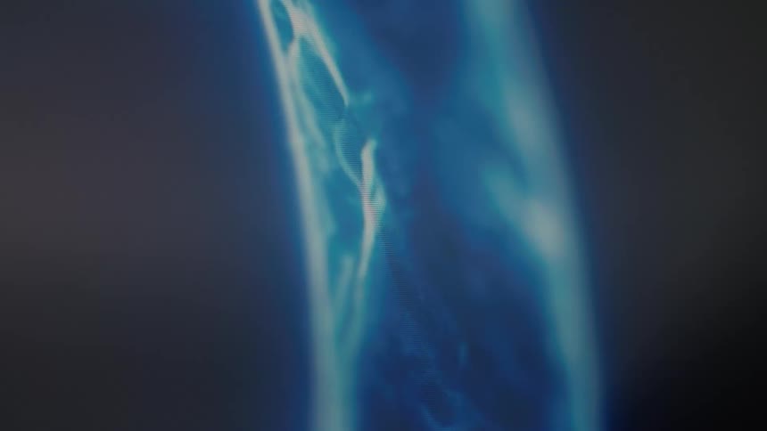 A mysterious blue digital energy wave composed of particles slowly materializes and shifts in the darkness