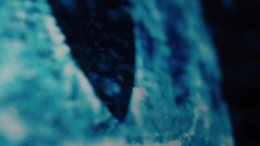 A serpentine line of glowing blue light glides across a curved, pixelated display in a dark, abstract environment