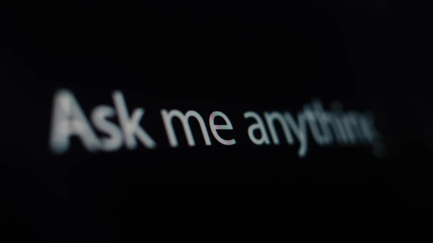 A close-up macro shot shows the phrase 'Ask me anything' being typed on a digital screen, symbolizing artificial intelligence and information search