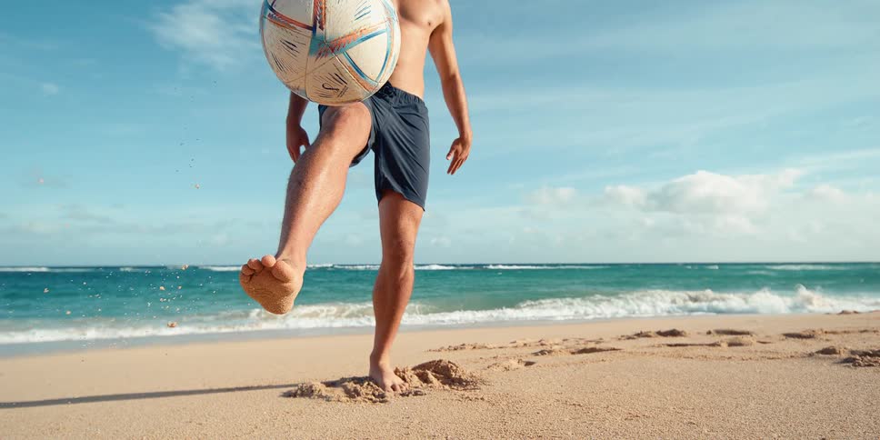 Super slow motion cinemagraph of a man juggling a soccer ball on his foot at the beach