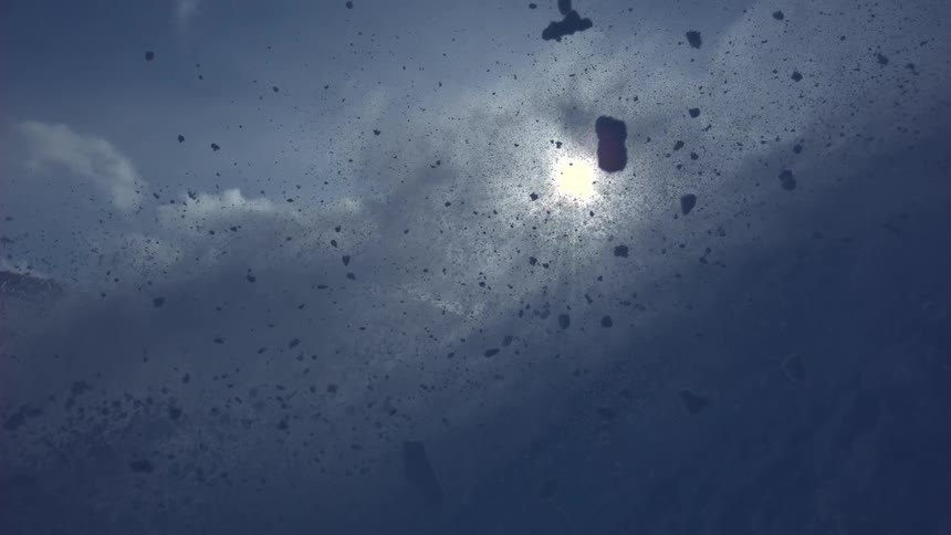Abstract slow-motion shot of snow spraying into the air, backlit by the bright winter sun