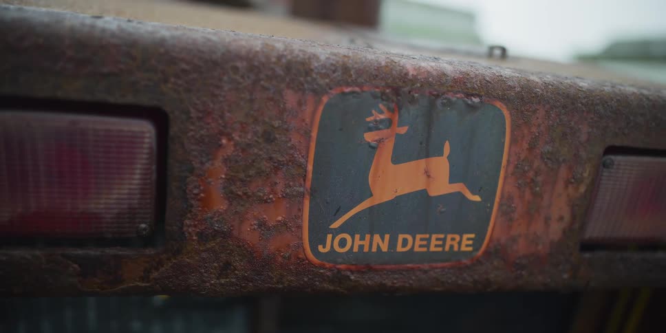 A detailed close-up shot shows the rusted logo on an old John Deere piece of farm equipment