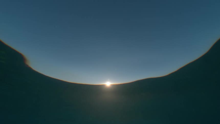 A serene and mesmerizing underwater view of the sun setting over the calm ocean surface