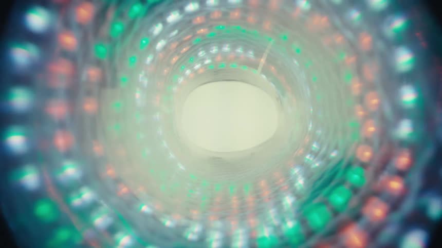 An abstract dolly zoom through a hypnotic tunnel of colorful, soft-focus lights that fades into a bright light at the end of the darkness