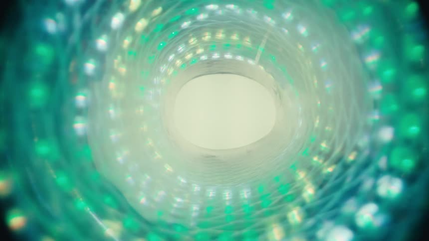 An abstract journey through a spiraling, glowing green light tunnel toward a bright white light at the end