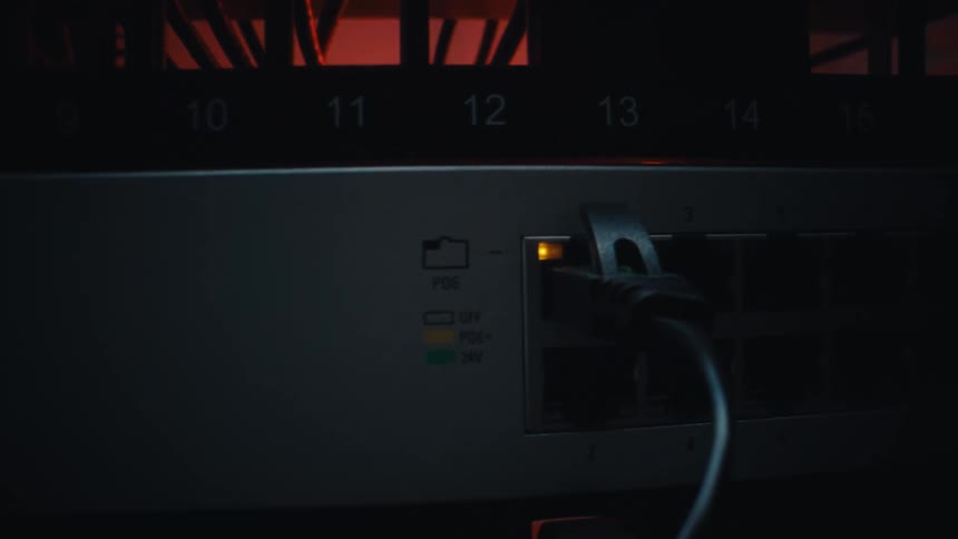 A close-up slow zoom on a blinking ethernet port light on a network switch in a dark server rack