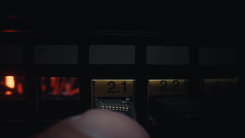 A macro close-up shot of a hand slowly inserting an internet cable into a server hub in a dark room