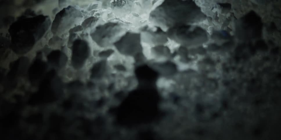 A dark and mysterious abstract shot of a rocky white landscape slowly revealed by a moving light
