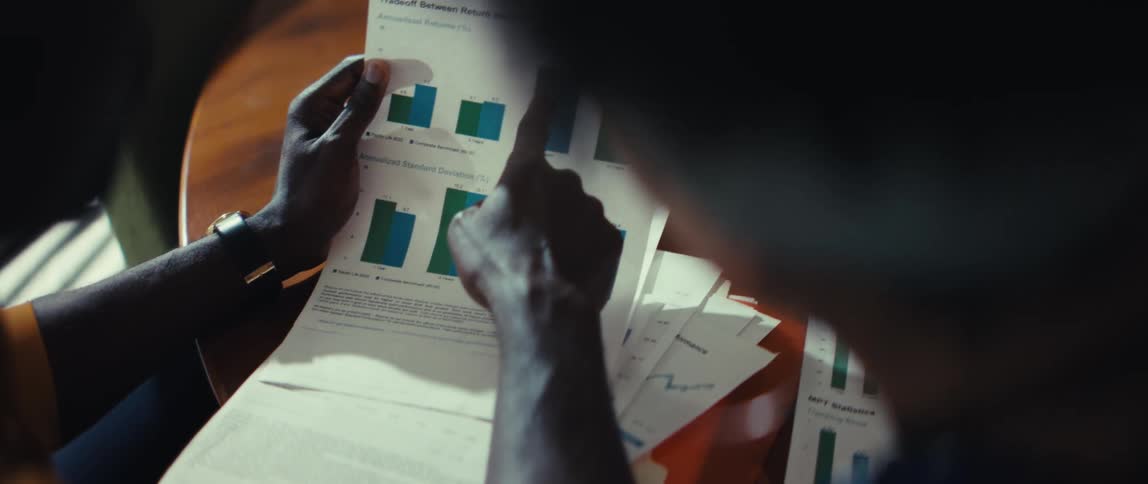 An over-the-shoulder perspective of two colleagues collaborating and analyzing financial performance charts and data