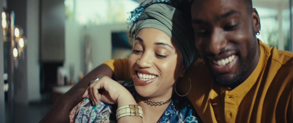 A happy young couple smiles with love and joy as they look at their newborn baby at home