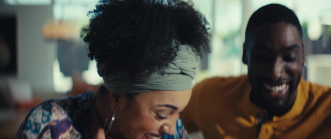 A joyful and affectionate young Black couple laughs together in a close-up slow motion shot