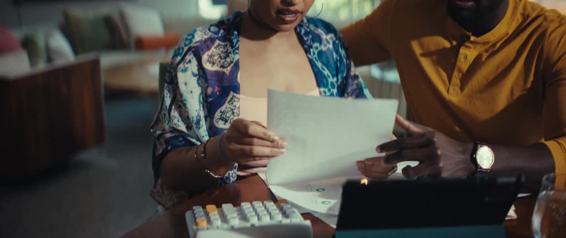 A happy young couple feels relieved and successful while reviewing their financial documents and paperwork together at home
