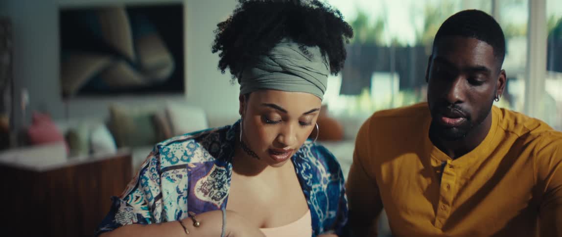 A man and woman review paperwork, with the woman showing surprise and then relief as they reach a decision together in their modern home
