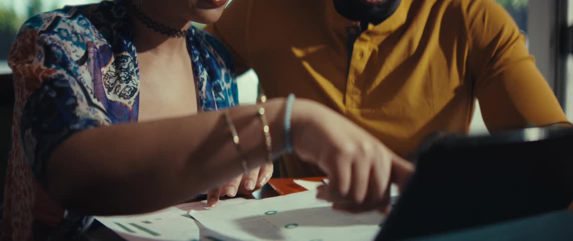 Close up of a young couple collaborating on their budget, reviewing financial documents with a calculator and tablet