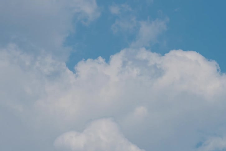 Time-lapse of fluffy white cumulus clouds moving across a bright blue sky