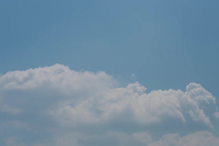 A calming time-lapse captures the gentle movement of white clouds against a bright blue sky