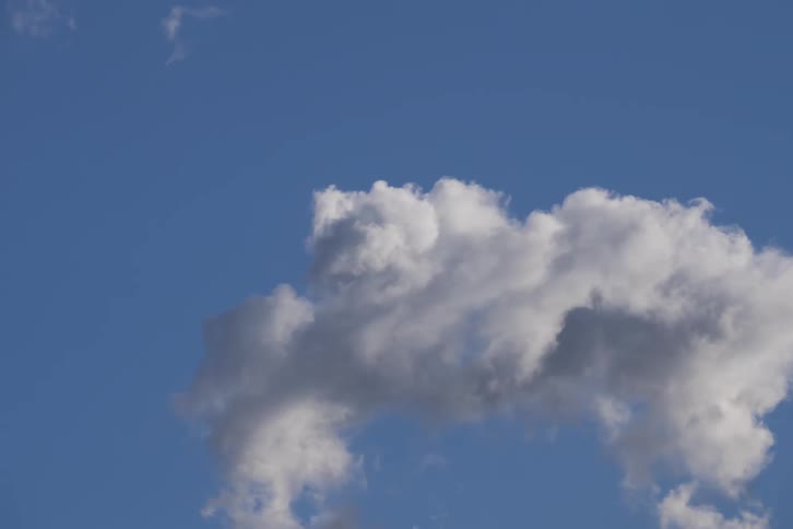 Time-lapse of a large, white cumulus cloud slowly dissipating against a vibrant blue sky