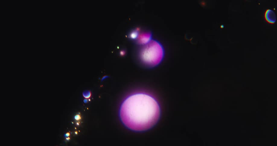 Colorful, magical bokeh lights and lens flares float and sparkle against a dark background