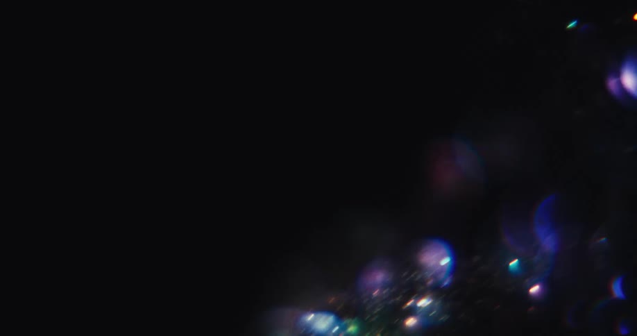 A mesmerizing vortex of colorful, shimmering bokeh lights and glitter particles swirls in a dark, abstract background