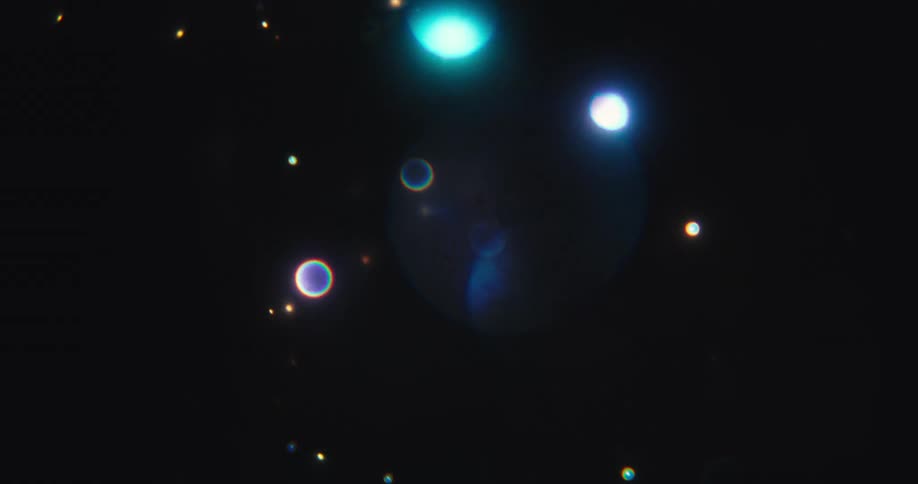 Colorful abstract bokeh lights and lens flares float and drift across a dark background