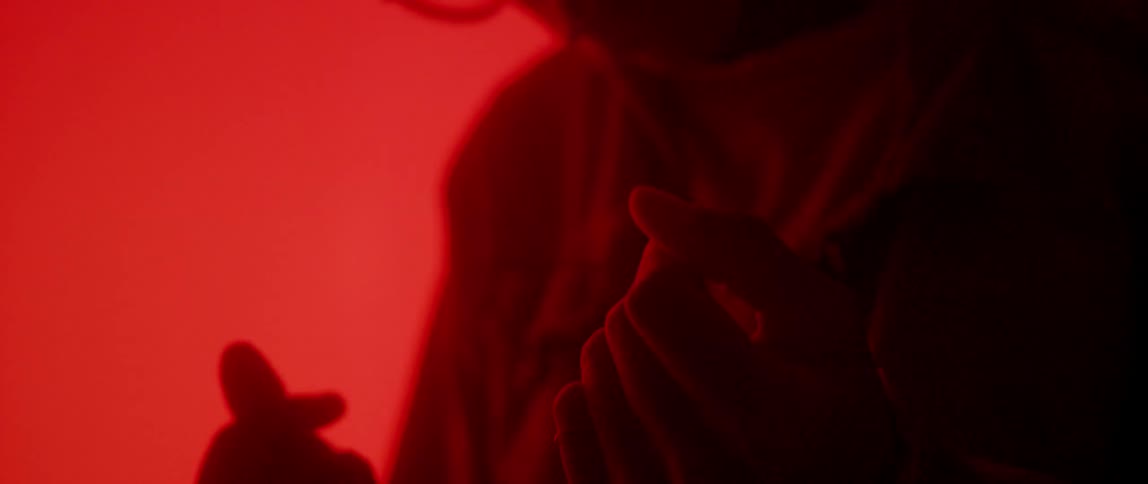A person snaps their fingers with a red glow all around