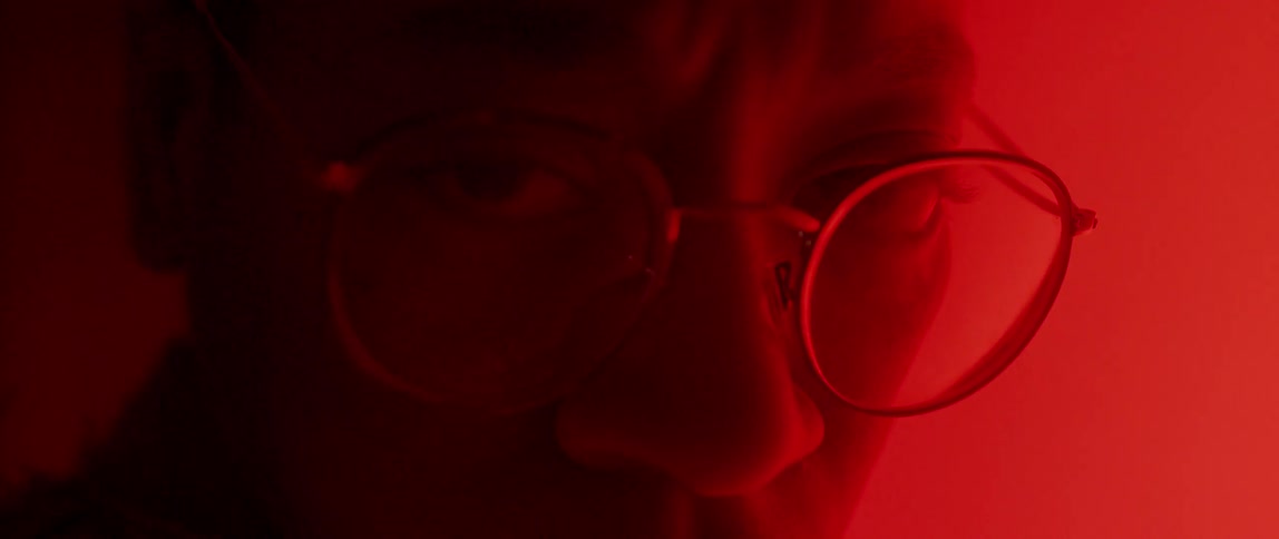 Close up of a persons glasses looking at a red screen