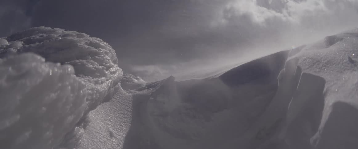 Extreme blizzard conditions as strong winds blow snow across a stark, frozen landscape