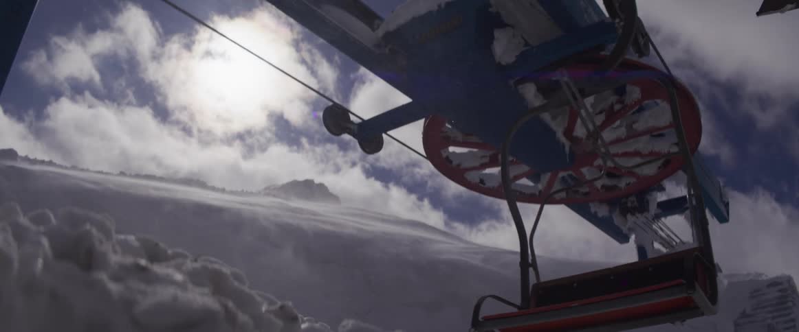 Dramatic shot of a snow-covered ski lift with an empty chair swinging in a blizzard on a sunny but cold mountain