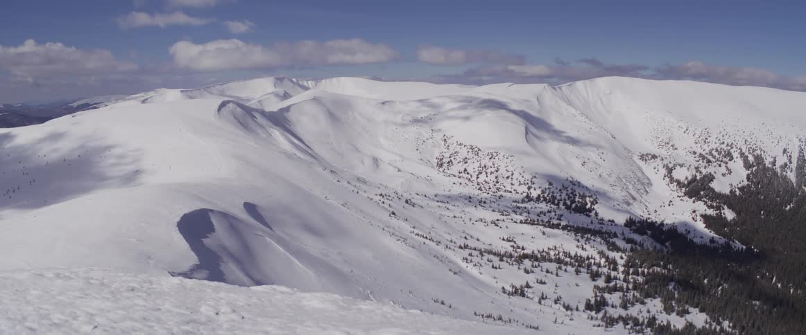 Expansive winter landscape view of a snow-covered mountain range on a sunny day