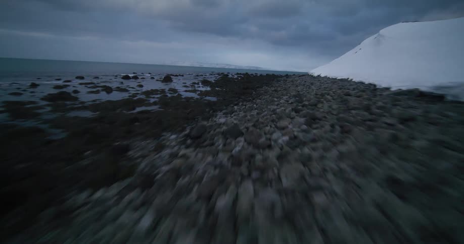 A dramatic FPV flight reveals traditional turf-roofed houses buried in snow along a desolate Nordic coastline before heading out to sea