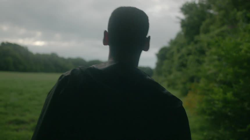 A man walks into an open field while looking around